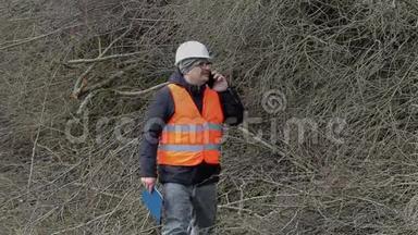 Lumberjack用智能手机聊天，在一堆树枝附近散步